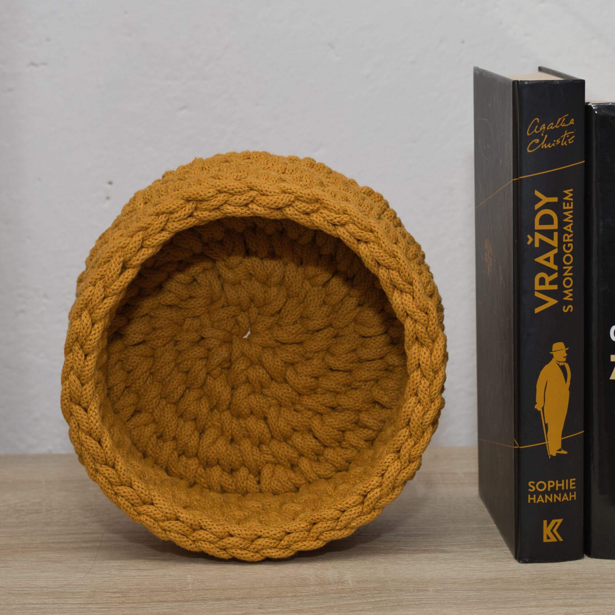 Tento ručne vyrobený okrúhly háčkovany košík v horčicovej farbe dodá každému priestoru štipku tepla a šarmu.